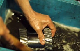 工場で製造された歯車を水に漬けるスタッフ